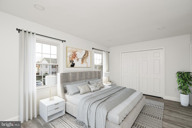 bedroom with a closet, recessed lighting, baseboards, and wood finished floors