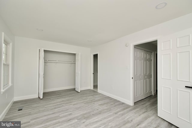 unfurnished bedroom featuring visible vents, light wood-style floors, baseboards, and a closet