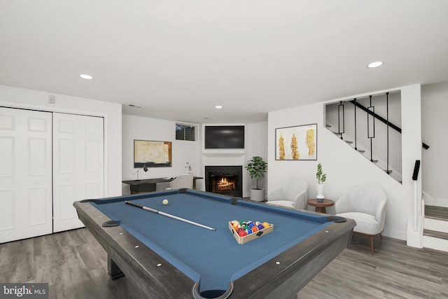 rec room featuring recessed lighting, visible vents, a warm lit fireplace, and wood finished floors