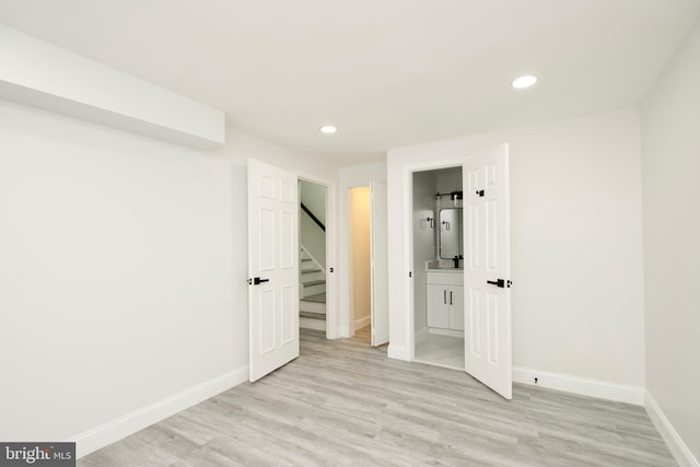 unfurnished bedroom with light wood-style flooring, ensuite bath, water heater, recessed lighting, and baseboards