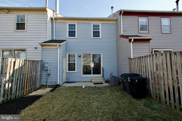 rear view of house with entry steps, a lawn, a fenced backyard, and central AC