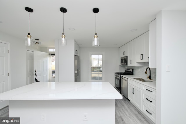 kitchen with a sink, backsplash, a center island, stainless steel appliances, and white cabinets