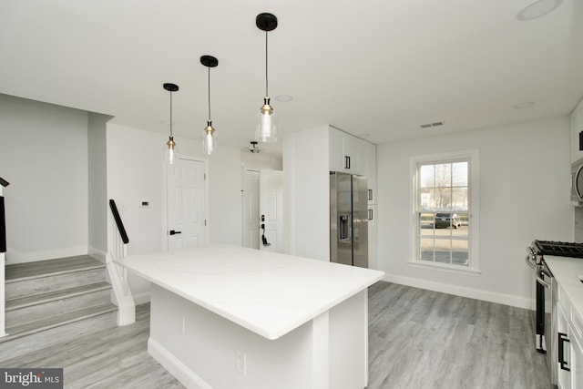 kitchen featuring light wood-type flooring, light stone countertops, appliances with stainless steel finishes, and visible vents