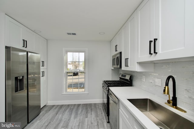 kitchen with a sink, light countertops, white cabinets, appliances with stainless steel finishes, and tasteful backsplash