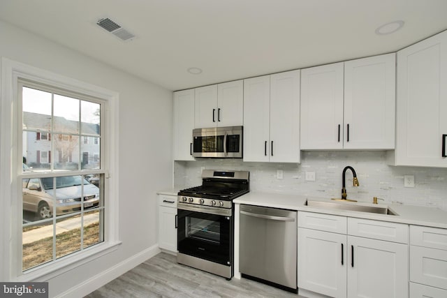 kitchen with tasteful backsplash, visible vents, stainless steel appliances, and a sink