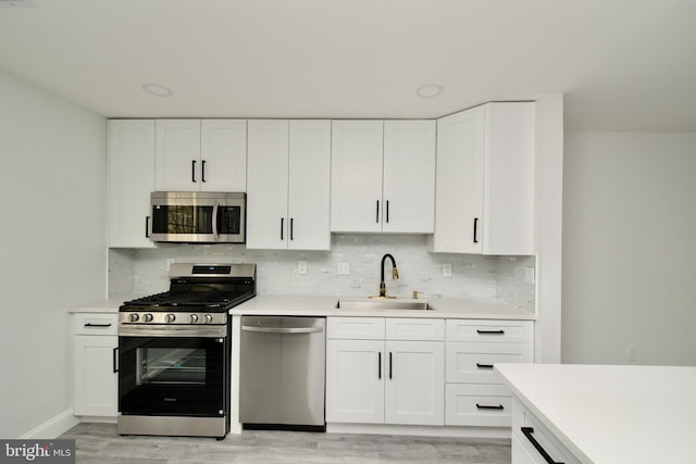 kitchen featuring light countertops, backsplash, appliances with stainless steel finishes, and a sink