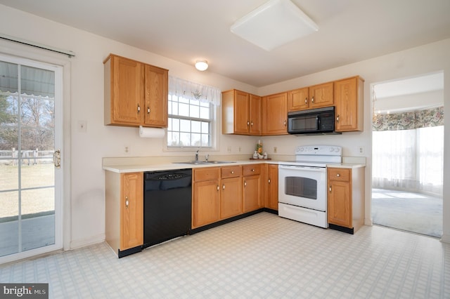 kitchen with light floors, baseboards, a sink, black appliances, and light countertops