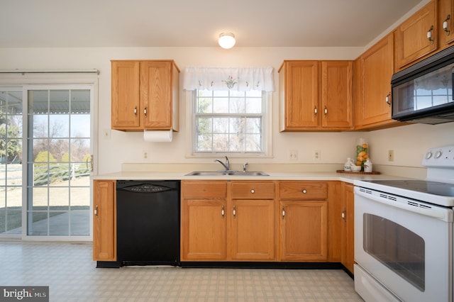 kitchen with a sink, light floors, black appliances, and light countertops