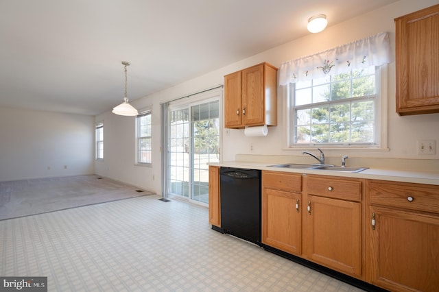 kitchen with baseboards, decorative light fixtures, light countertops, black dishwasher, and a sink