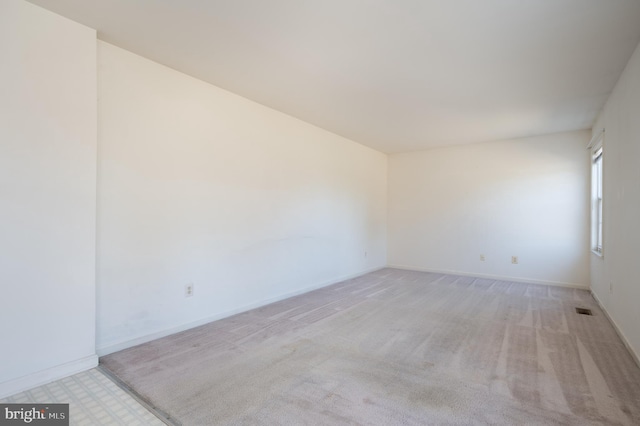 spare room featuring visible vents, baseboards, and light colored carpet