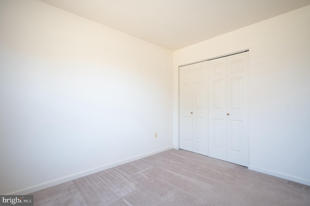 unfurnished bedroom with carpet, baseboards, and a closet