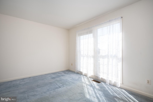 unfurnished room with visible vents, carpet, and baseboards