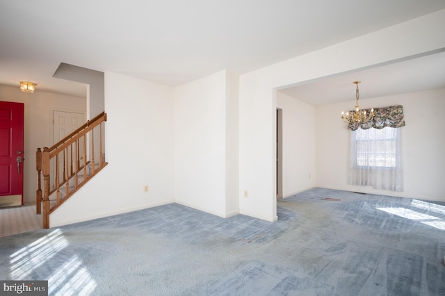 carpeted empty room featuring stairway, baseboards, and an inviting chandelier