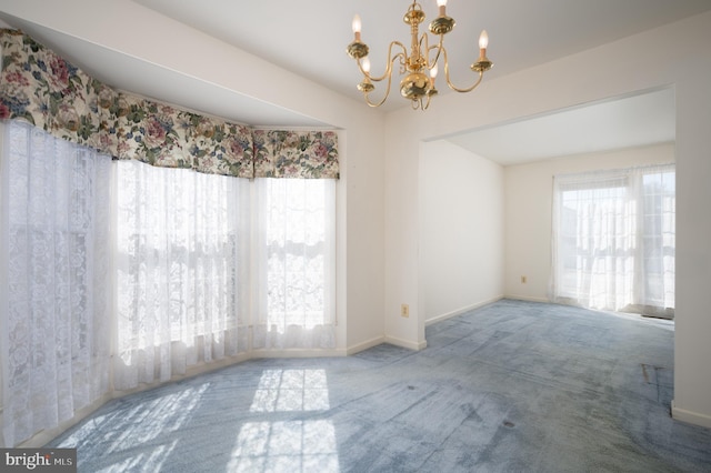 carpeted spare room featuring a chandelier and baseboards