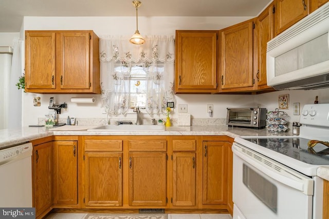 kitchen with a sink, white appliances, brown cabinetry, and light countertops