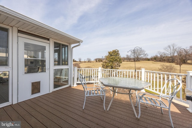 wooden deck with a rural view and outdoor dining space