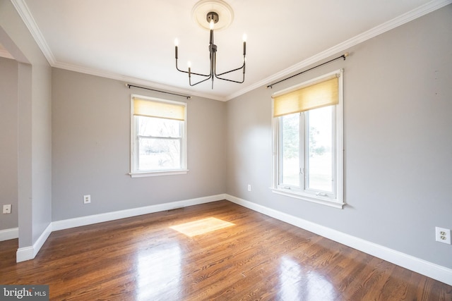 empty room featuring wood finished floors, visible vents, baseboards, ornamental molding, and a notable chandelier