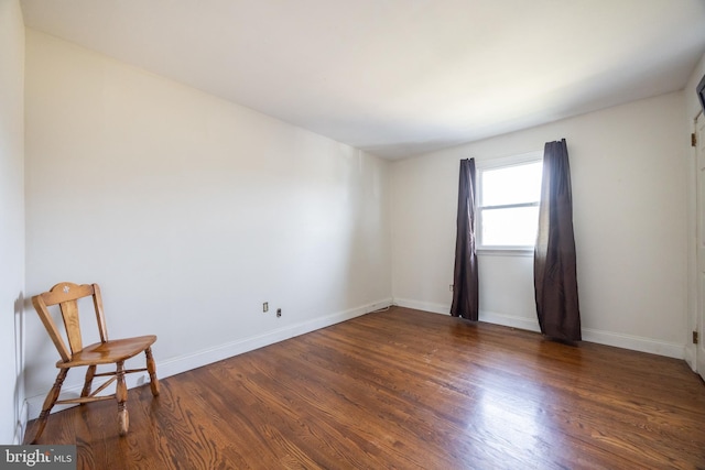 spare room with baseboards and wood finished floors