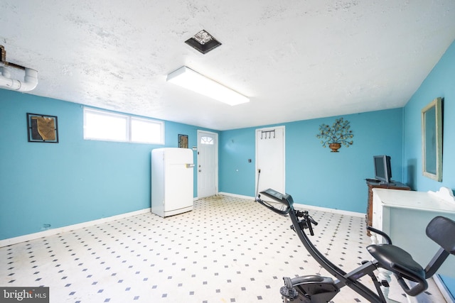 exercise room featuring baseboards and a textured ceiling