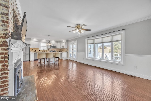 unfurnished living room with crown molding, a fireplace, and dark wood-style flooring