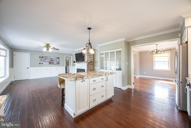 kitchen featuring light stone counters, white cabinetry, a fireplace, and freestanding refrigerator