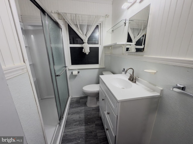 full bath with vanity, toilet, wood finished floors, and a stall shower