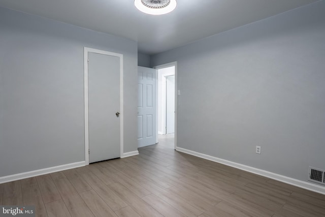 spare room with visible vents, baseboards, and wood finished floors