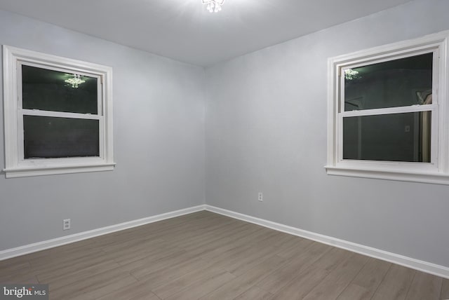 spare room with baseboards and wood finished floors