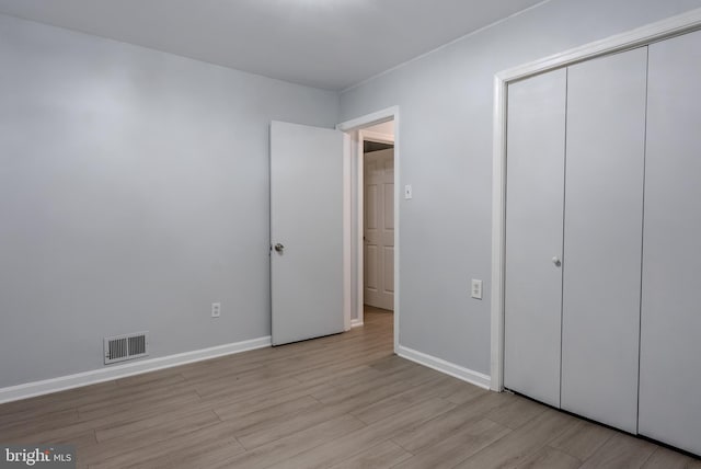 unfurnished bedroom featuring a closet, visible vents, light wood-style flooring, and baseboards