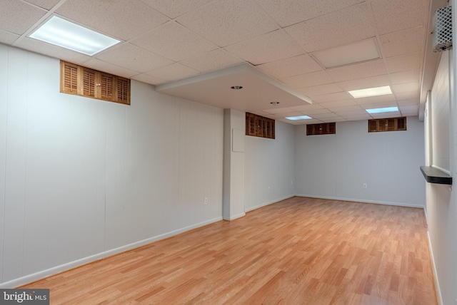 finished below grade area with visible vents, a paneled ceiling, baseboards, and wood finished floors