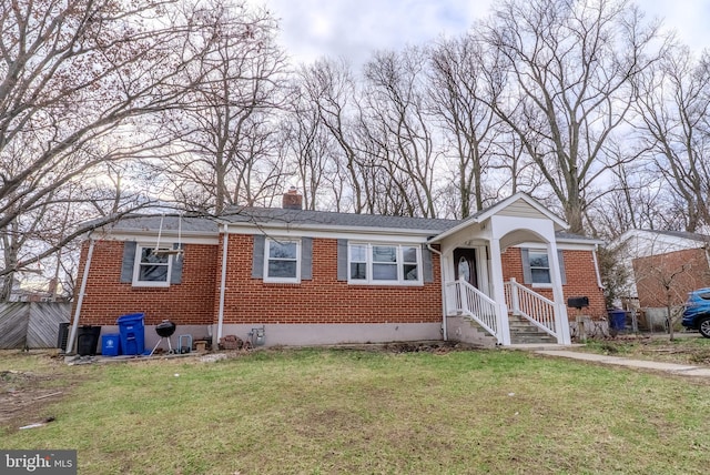 view of front facade featuring brick siding, a chimney, and a front yard