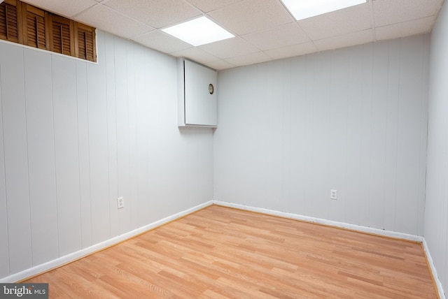 spare room with a drop ceiling, light wood-style flooring, and baseboards