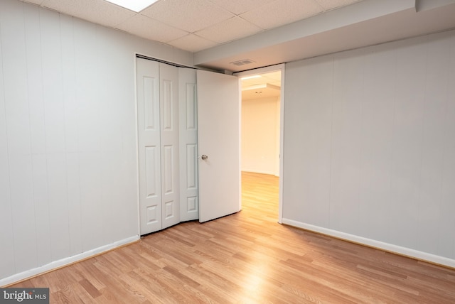 unfurnished bedroom featuring light wood finished floors, visible vents, baseboards, a closet, and a paneled ceiling