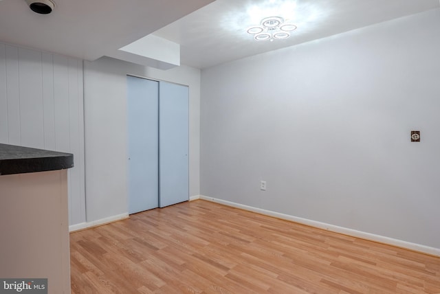 unfurnished bedroom featuring a closet, baseboards, and light wood finished floors