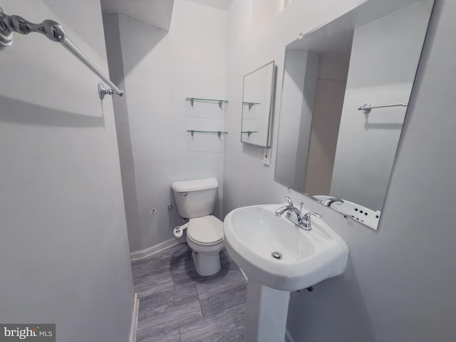 bathroom featuring toilet, baseboards, and a sink