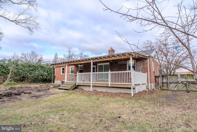 view of front of property with brick siding, a chimney, a front lawn, and fence