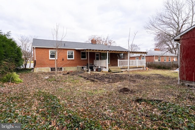 back of property with brick siding, a deck, and fence