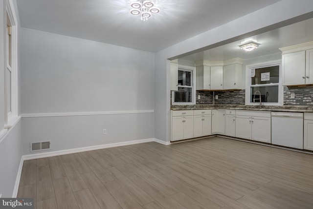 kitchen featuring dishwasher, visible vents, backsplash, and light wood-type flooring