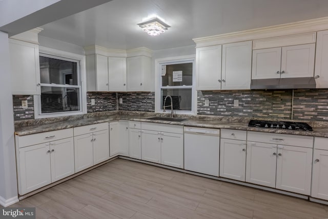 kitchen with a sink, under cabinet range hood, gas cooktop, tasteful backsplash, and white dishwasher