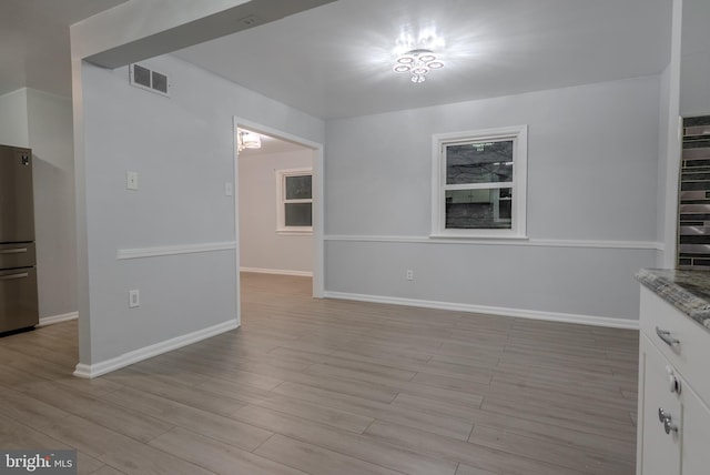 unfurnished dining area with light wood-type flooring, baseboards, and visible vents