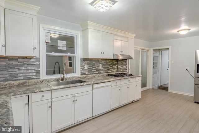 kitchen featuring light wood finished floors, a sink, stainless steel appliances, under cabinet range hood, and white cabinetry