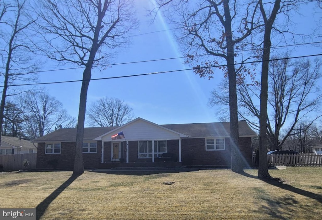 ranch-style house with a front lawn, fence, and brick siding