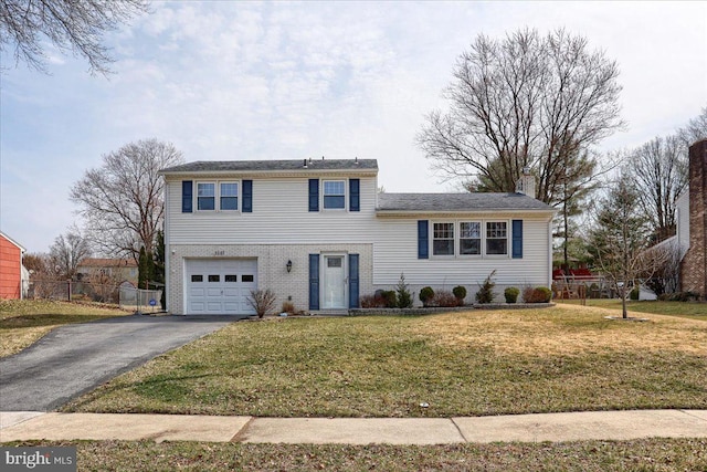 split level home featuring a front yard, fence, driveway, a garage, and brick siding