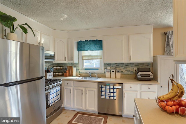 kitchen featuring white cabinetry, light countertops, appliances with stainless steel finishes, and a sink