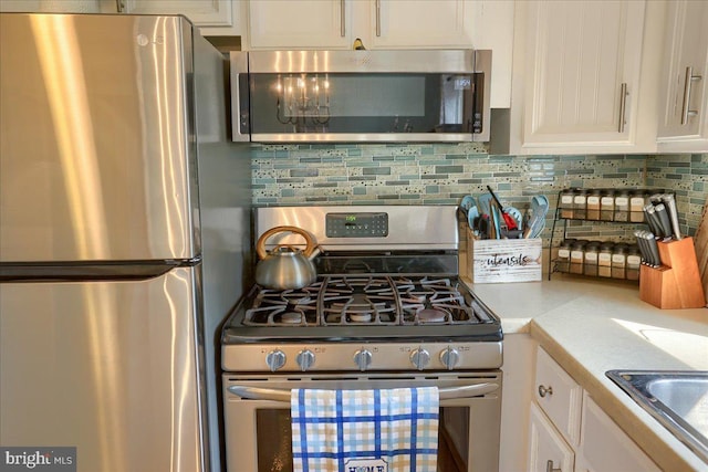 kitchen with backsplash, white cabinets, stainless steel appliances, and light countertops