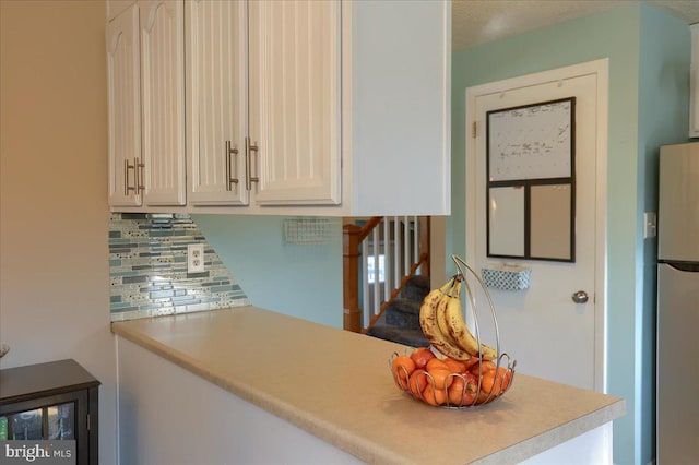 kitchen featuring tasteful backsplash, freestanding refrigerator, and light countertops