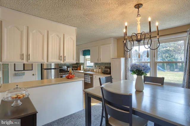 kitchen with backsplash, white cabinetry, fridge, light countertops, and a chandelier