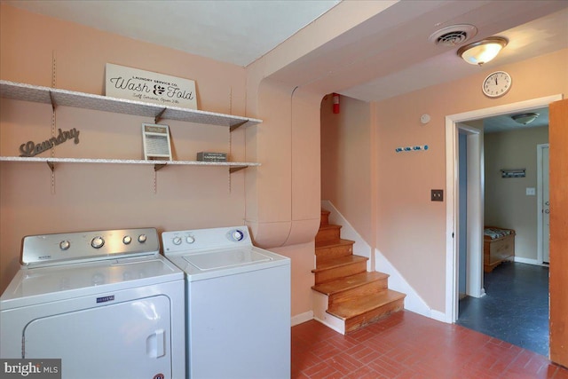 laundry room featuring visible vents, washing machine and dryer, brick floor, baseboards, and laundry area