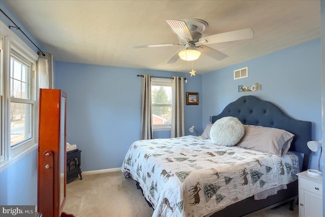 bedroom featuring visible vents, ceiling fan, baseboards, light carpet, and a wood stove