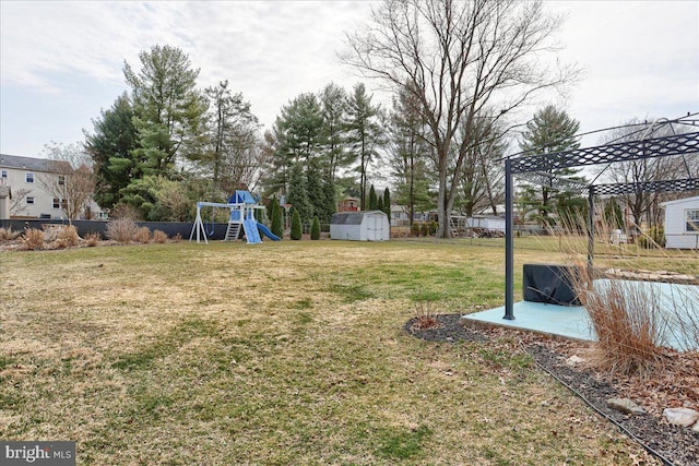 view of yard with an outbuilding, a patio, fence, a storage unit, and a playground